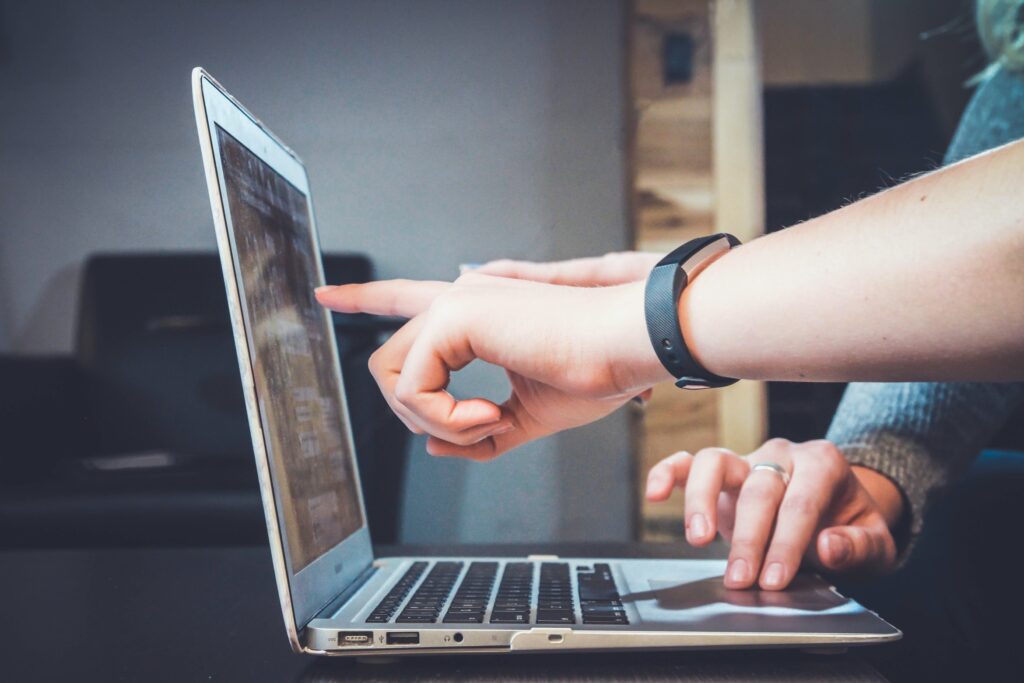 Two people working on a laptop, one pointing at the screen while the other has their hand on the keyboard, as if strategizing their next adventure to Lake Martin.