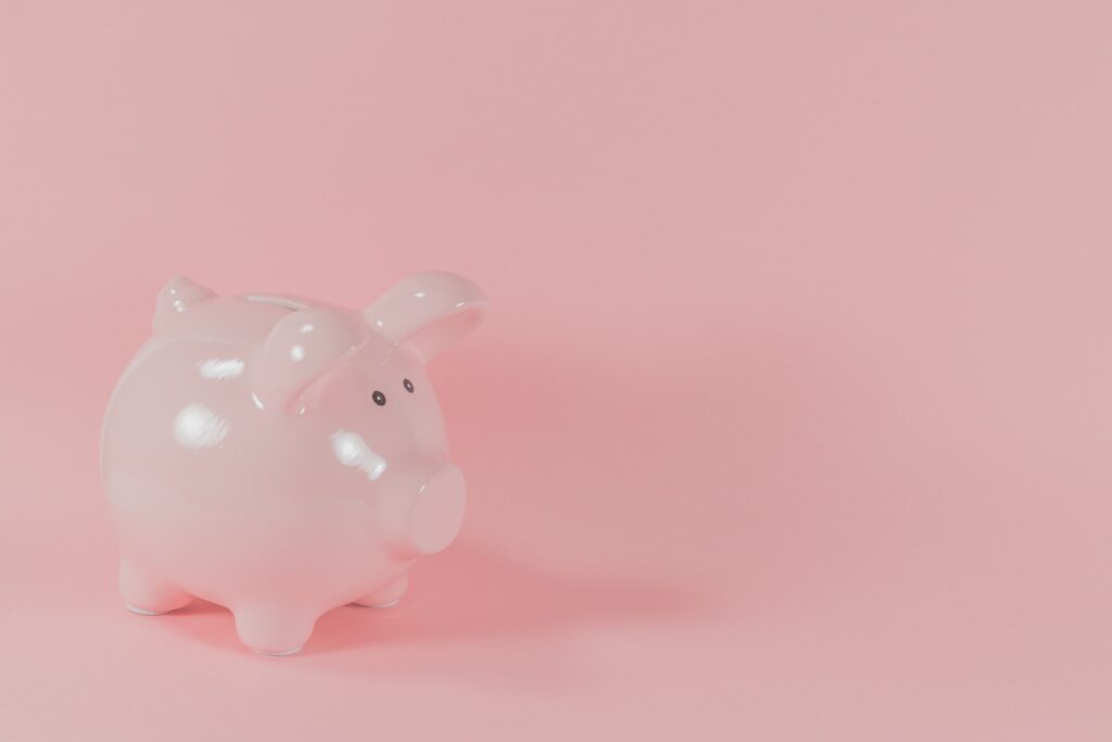 A small, glossy pink piggy bank is positioned on the left side of the image, set against a plain pink background, reminiscent of serene moments by Lake Martin.