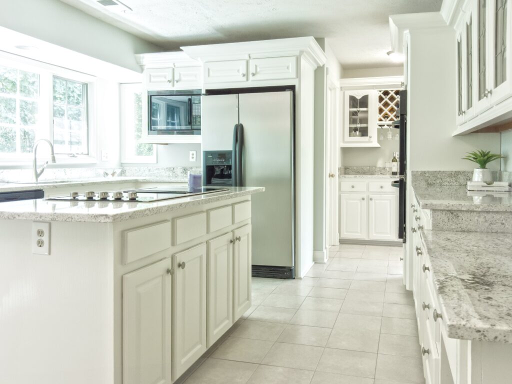 A kitchen with white cabinets and tile floors.