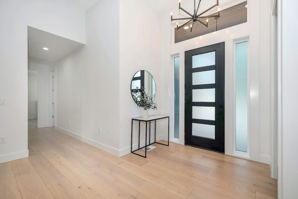 A foyer with a black door and white walls.