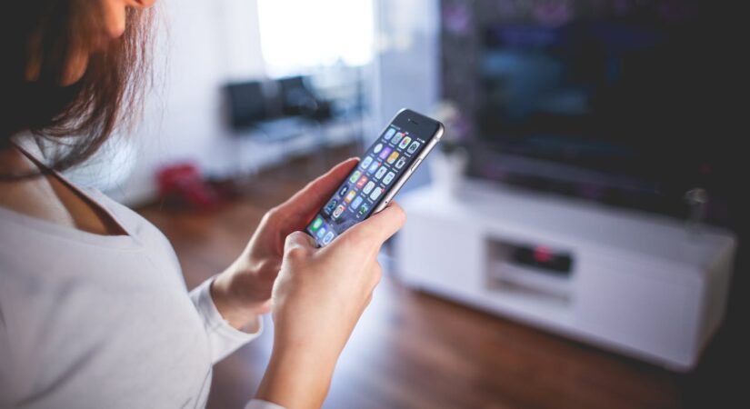 Woman using smartphone with apps open.