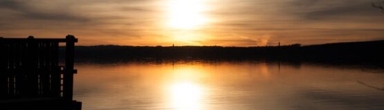 Sunset reflected in calm lake water.